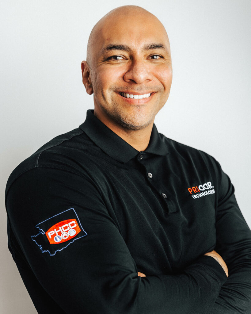 Headshot of PRICOR Technologies co-founder Wiley Cortez smiling in a black button down shirt with his arms folded.